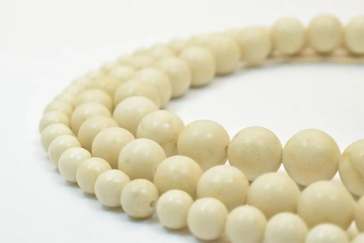 Close-up of natural ivory bead necklace on white background.