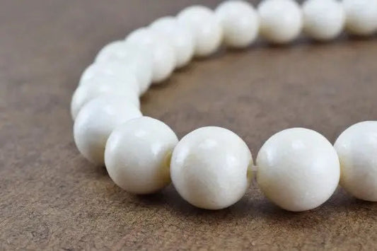 White pearl bead necklace on brown background.