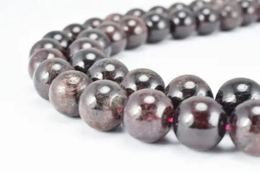 Close-up of polished garnet bead necklace on white background.