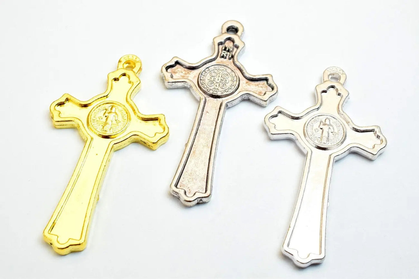 Gold and silver crucifix pendants with engraved medallion designs.