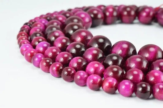 Pink and burgundy beaded necklace close-up on white background.