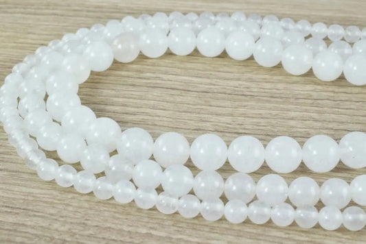 White round gemstone beads on a wooden surface.