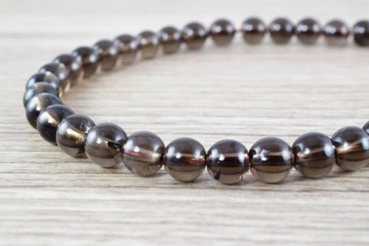 Smoky quartz beaded bracelet on wooden surface.