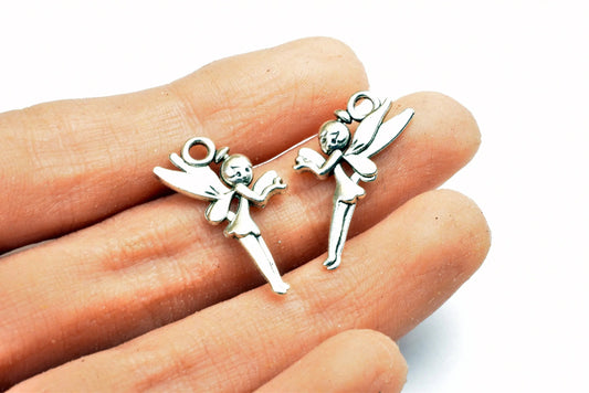 "Silver fairy charms held in hand for jewelry making"