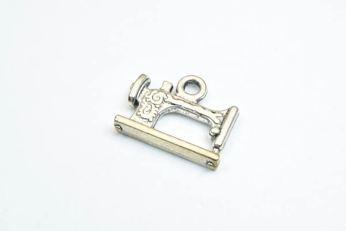 Vintage sewing machine charm pendant in silver tone.