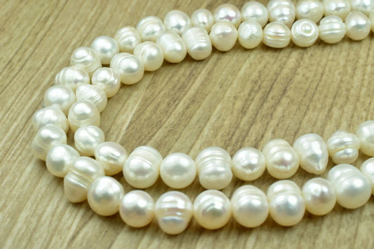 Alt text: "Strand of white freshwater pearls on wooden surface"