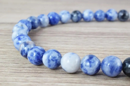 Blue and white sodalite gemstone bead bracelet on wooden surface.