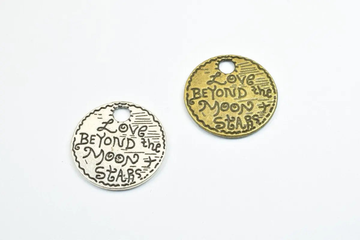 Two engraved metal charms reading "Love Beyond the Moon and Stars," in silver and bronze.