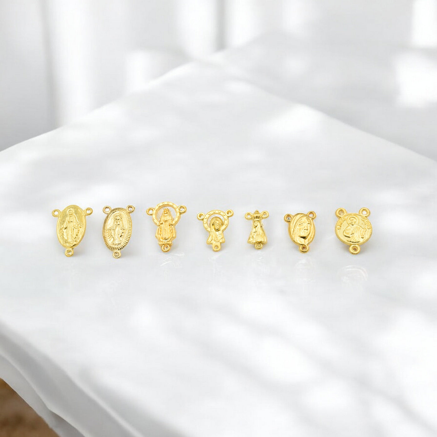 Gold religious medallion charms set on white background.