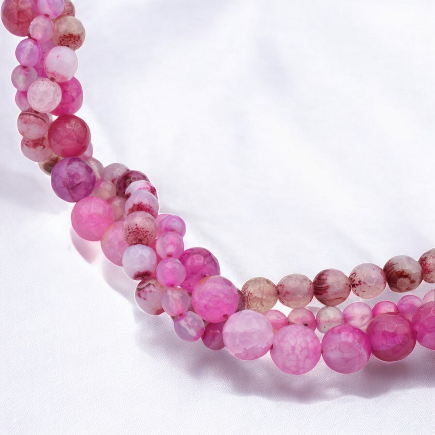 Pink gemstone beaded necklace on white background.