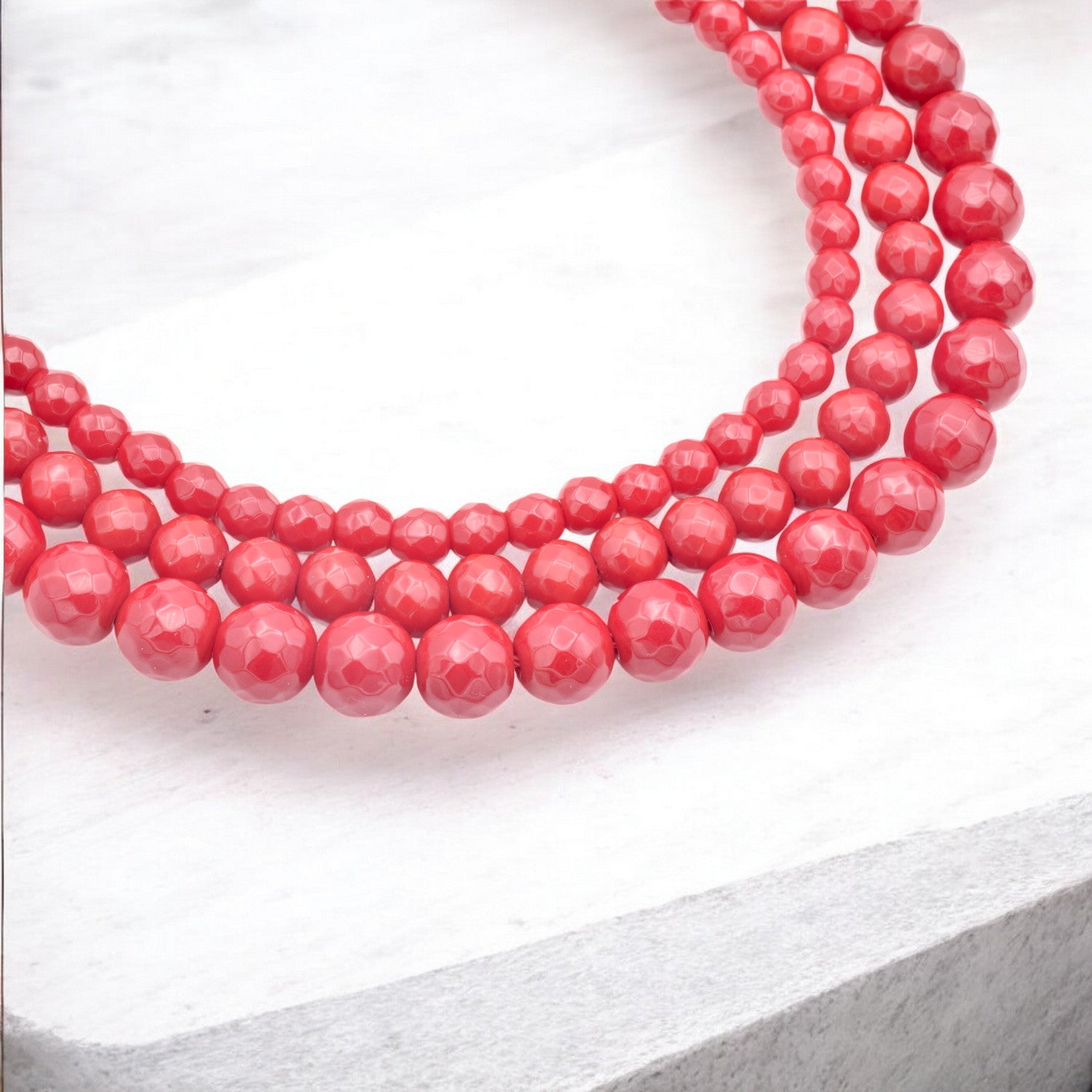 Red beaded necklace on a white background.