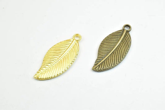 Gold and bronze leaf-shaped metal charms on white background.