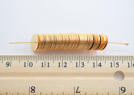 Gold spacer beads on wire with ruler for size reference.