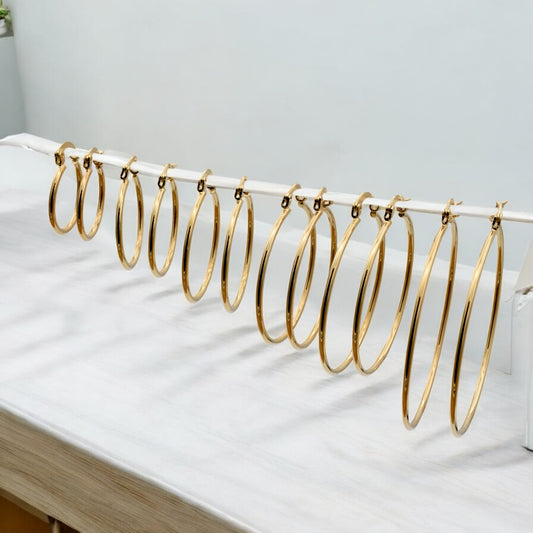 Display of gold hoop earrings in various sizes arranged on a stand, showcasing their sleek and polished finish.