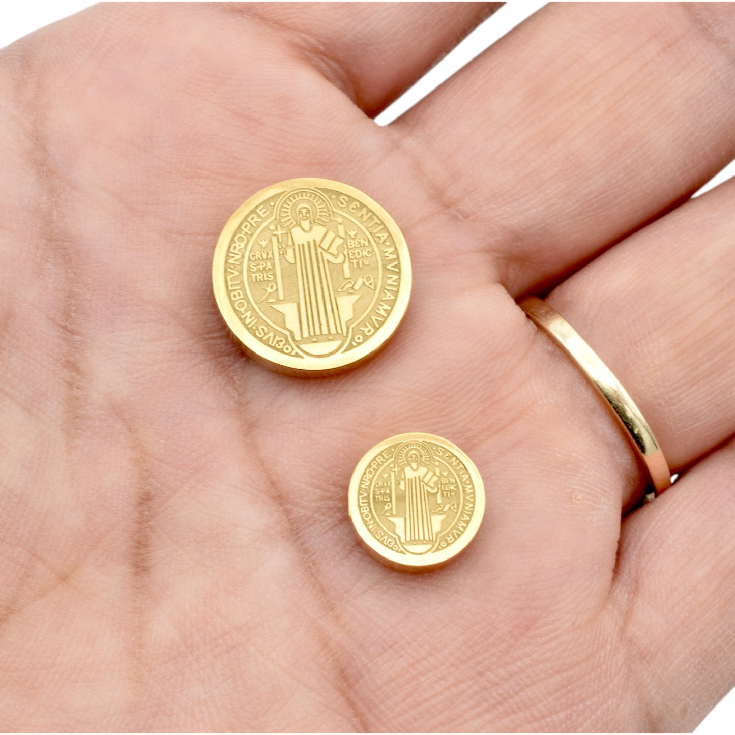 "Gold Saint Benedict medallion coins in palm"