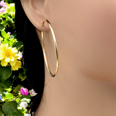 Close-up view of chunky gold hoop earrings with a polished finish, placed on a fabric background for an elegant look.