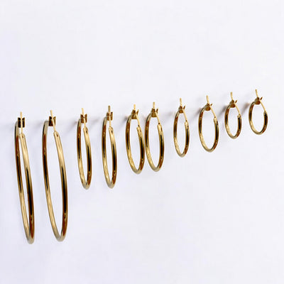 Close-up view of chunky gold hoop earrings with a polished finish, placed on a fabric background for an elegant look.