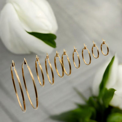 Close-up view of chunky gold hoop earrings with a polished finish, placed on a fabric background for an elegant look.