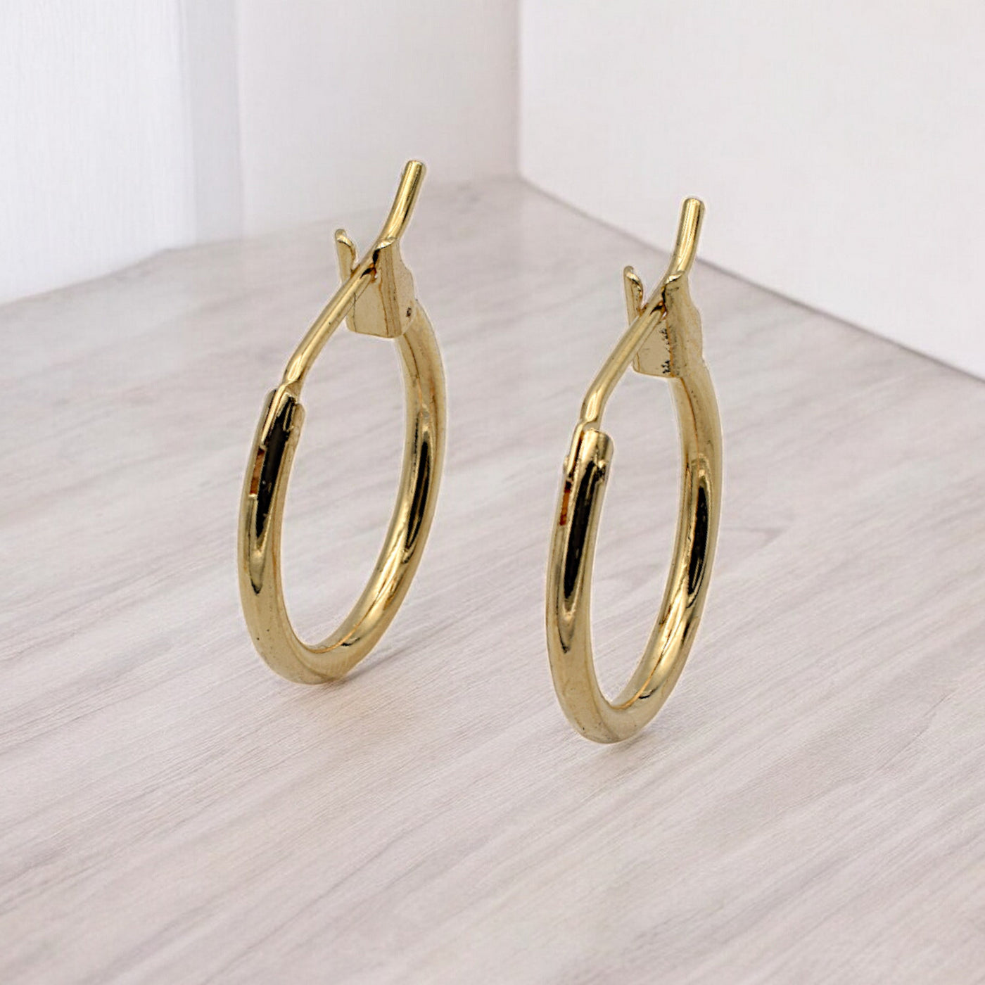 Close-up view of chunky gold hoop earrings with a polished finish, placed on a fabric background for an elegant look.
