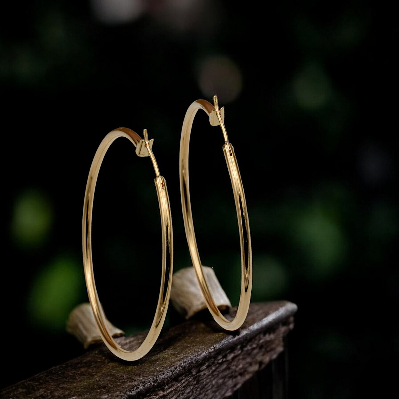 Close-up view of chunky gold hoop earrings with a polished finish, placed on a fabric background for an elegant look.