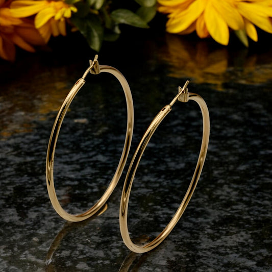 Close-up view of chunky gold hoop earrings with a polished finish, placed on a fabric background for an elegant look.