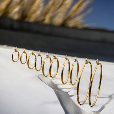 Close-up view of chunky gold hoop earrings with a polished finish, placed on a fabric background for an elegant look.