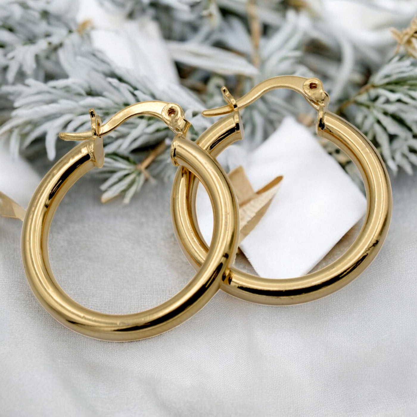 Set of gold hoop earrings in multiple sizes displayed on a black background, emphasizing their shiny, reflective surface and classic design.