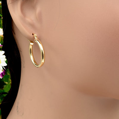 Set of gold hoop earrings in multiple sizes displayed on a black background, emphasizing their shiny, reflective surface and classic design.