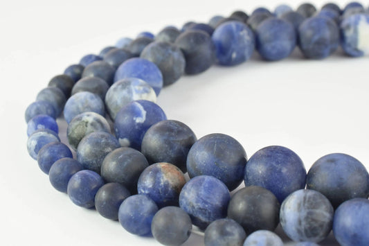 Blue sodalite gemstone beads on white background.