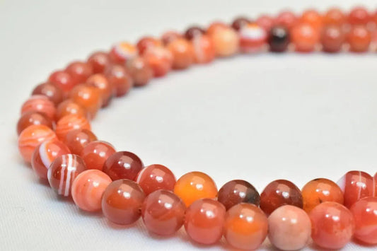 Red agate beaded necklace on white background.