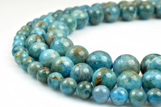 Blue apatite gemstone beads strand on white background.