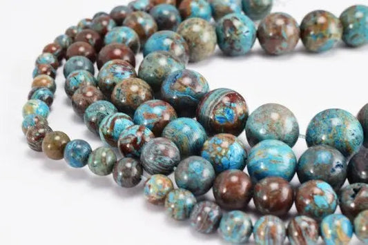 Multicolored natural gemstone beads in various sizes on white background.