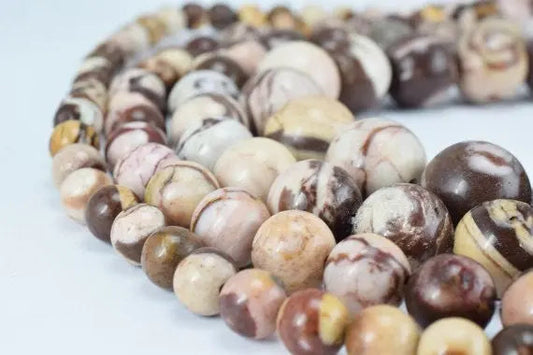 Polished marble beads in variegated browns and creams, close-up.