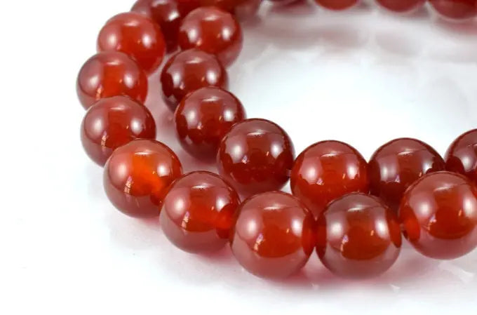 "Red carnelian gemstone beaded bracelet on white background"