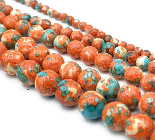 Colorful ceramic beads in orange, teal, and cream for jewelry making.