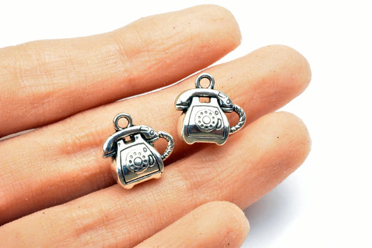 "Silver vintage telephone charms on fingertips for jewelry making"