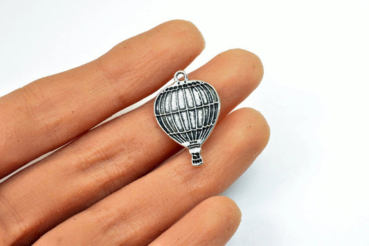 "Silver hot air balloon charm held in hand"