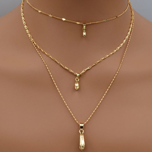 Three layered gold necklaces with teardrop pendants on display mannequin.