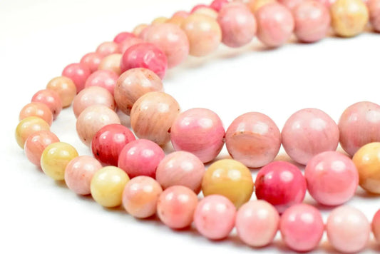 Pink and yellow opal bead necklace close-up on white background.