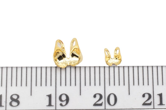 Gold butterfly earring backs with ruler for size comparison.