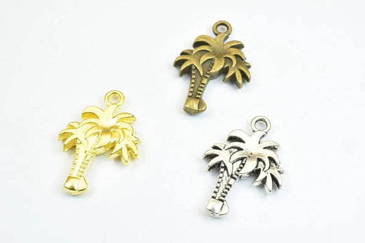 Three palm tree metal charms in gold, bronze, and silver.