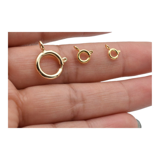 Three gold spring ring clasps on a hand.