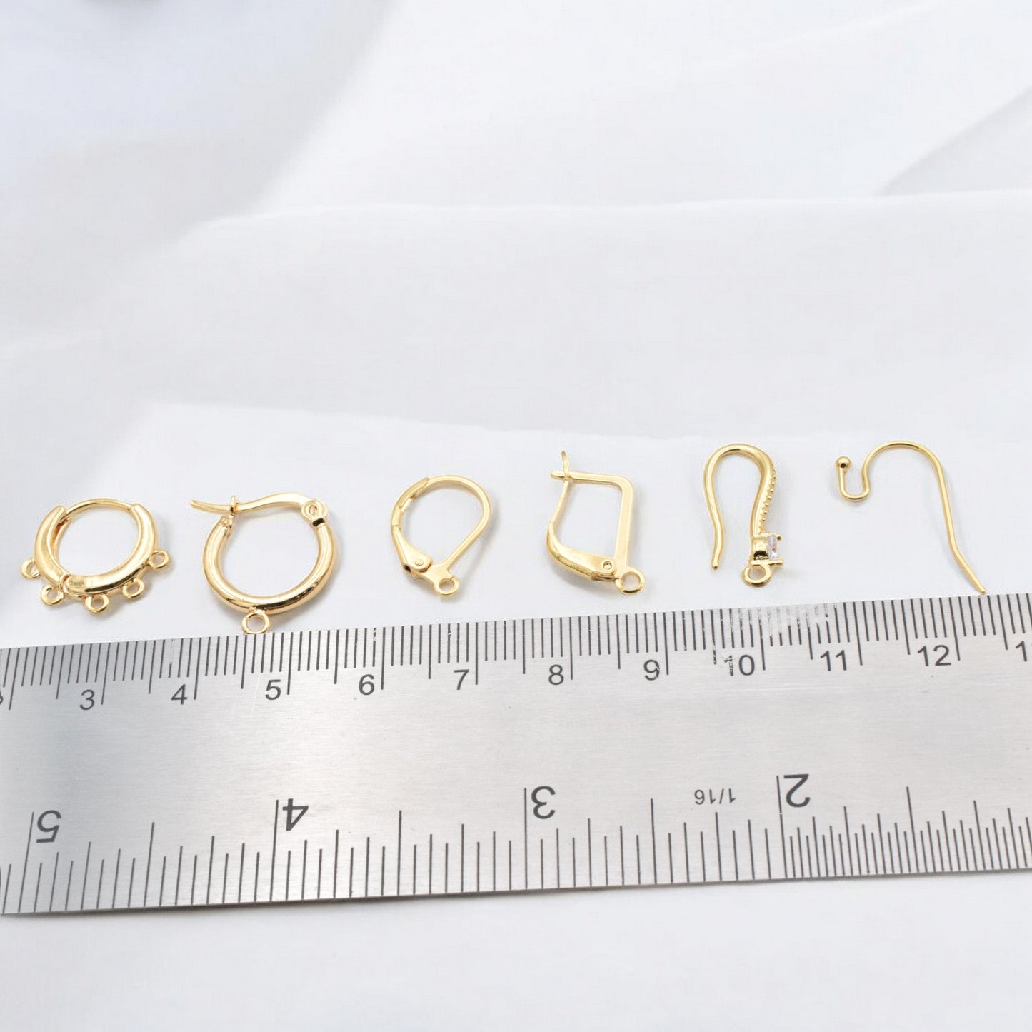 Gold earring hooks variety displayed with ruler for DIY jewelry making.