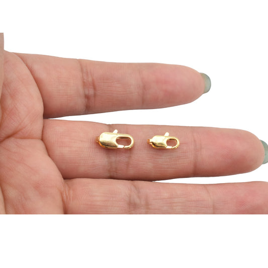 "Gold-plated lobster clasps on fingers for jewelry making"