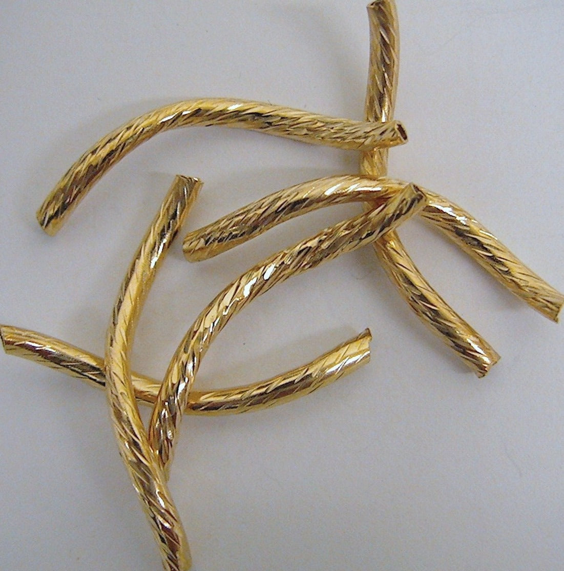 Gold twisted jewelry beads on white background.