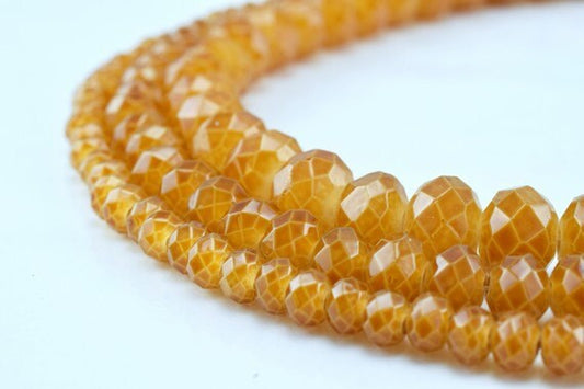 Faceted honey quartz gemstone beads strand on white background.