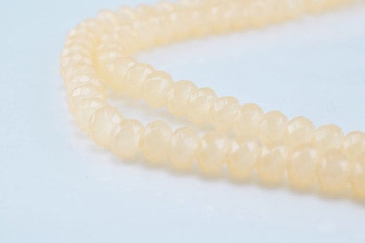 Faceted cream quartz bead strand on light background.