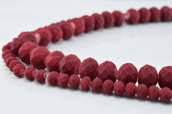 Red faceted agate beaded necklace on white background.