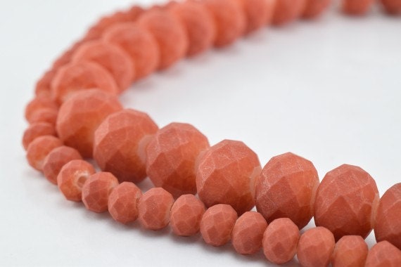 "Coral stone faceted bead necklace close-up on white background"