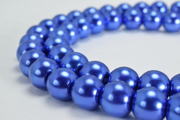 Blue pearl necklace strand close-up on white background.